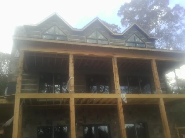 Dormers and porch framing on a large log home under construction — Roof Coating work by our crew in Muenster