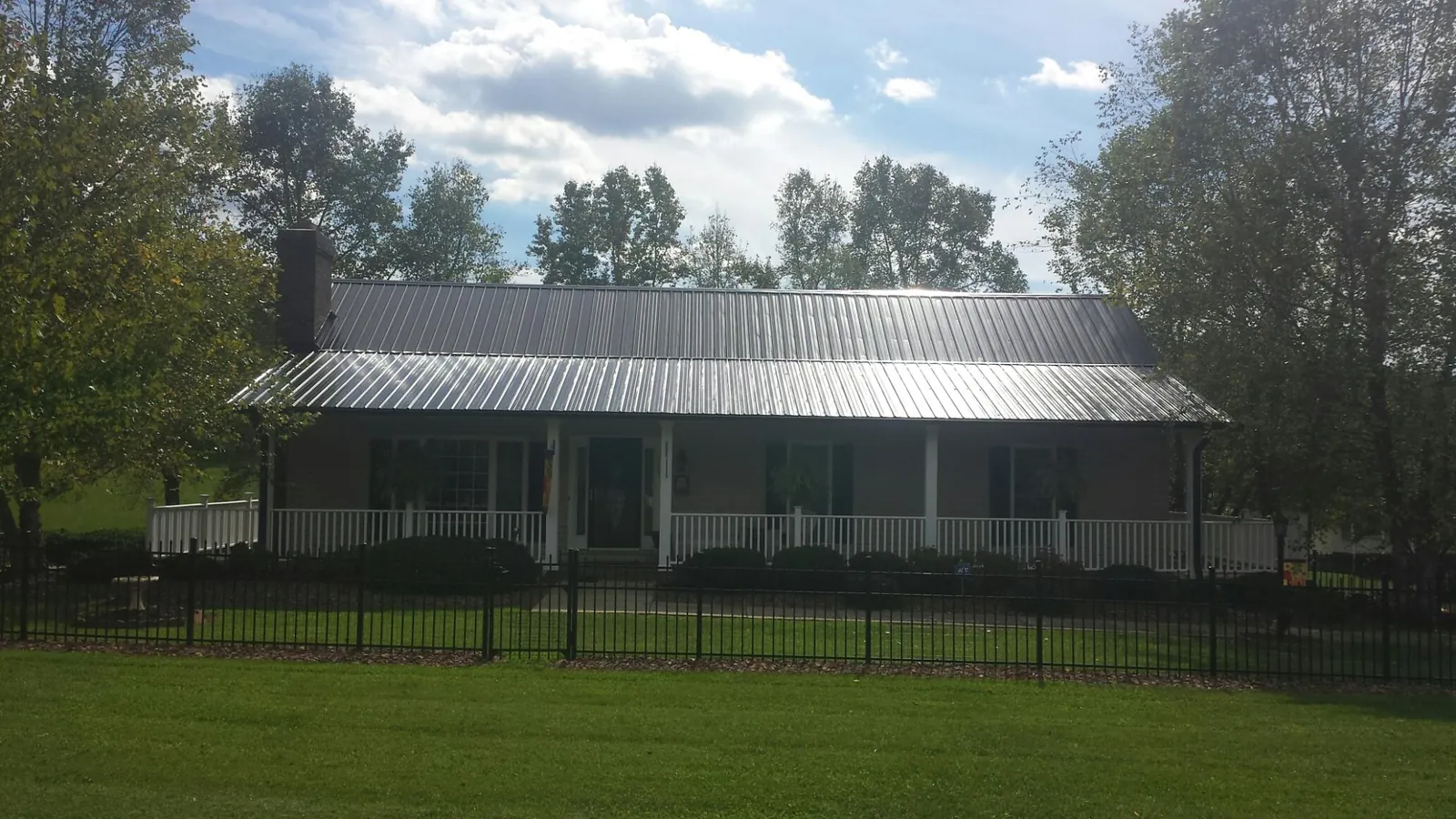 Gray metal roof on a brick ranch with a full width front porch — Gutter Guard Installation work by our crew in Muenster