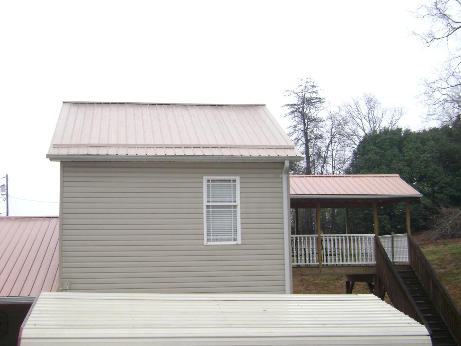 Tan metal roofs on a two story addition and attached porch, from a Roof Replacement job in Muenster