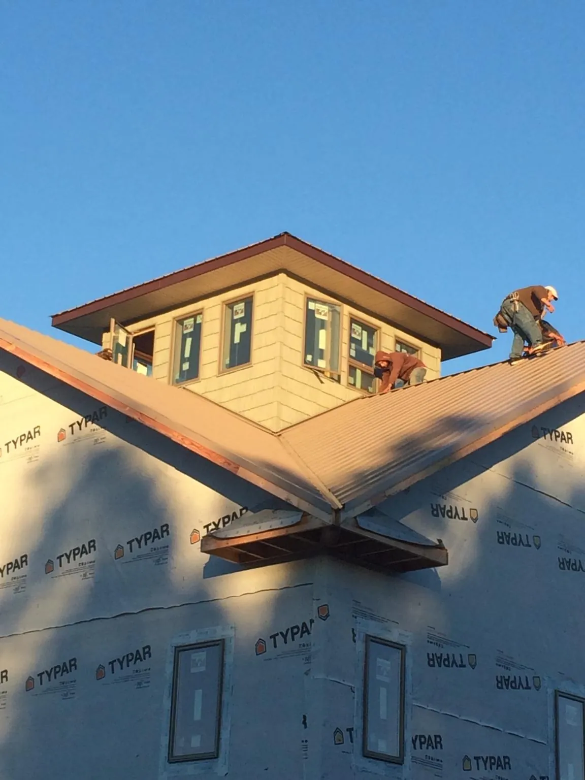 Roofers working around a rooftop cupola on a new metal roof at sunset — Roof Waterproofing in Muenster by Roofing Brothers